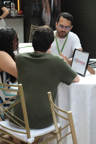 Expositor atendendo visitante com tablet na mesa