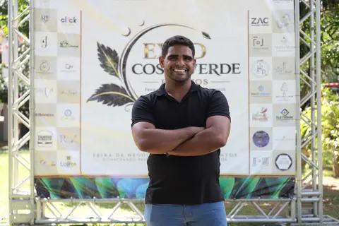 Marcos Santana de braços cruzados em frente ao telão oficial da Expo Costa Verde