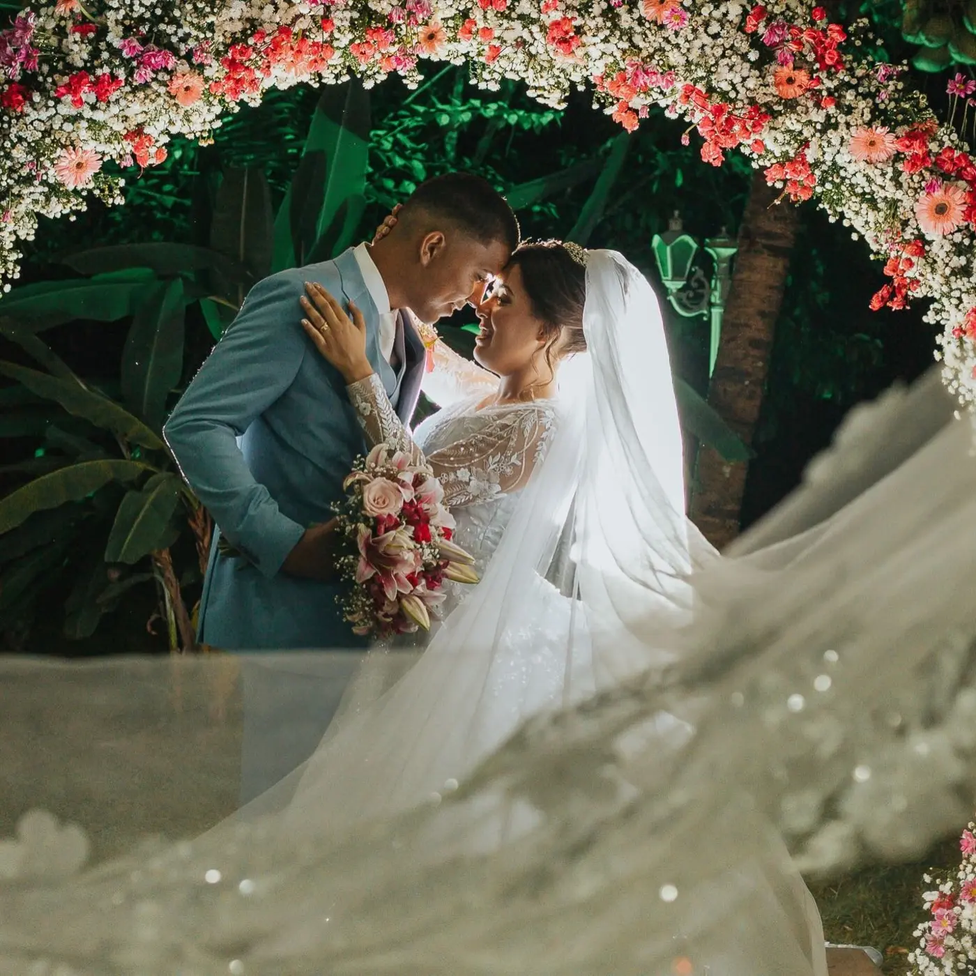 Casal de noivos sob arco de flores coloridas