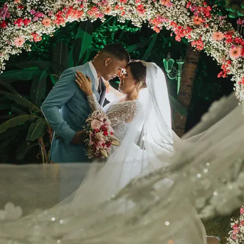 Casal de noivos sob arco de flores coloridas à noite