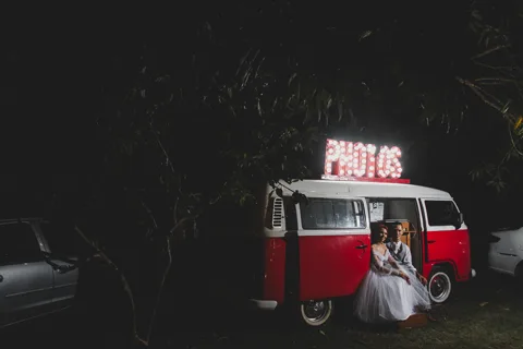 Kombi vermelha vintage com letreiro Photos iluminado, cabine de fotos da festa