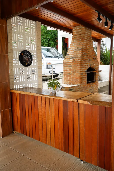 Área de churrasco com forno de tijolos e balcão de madeira