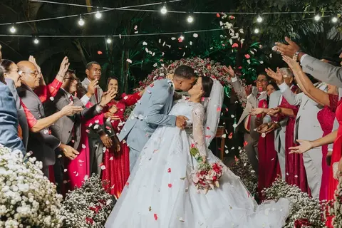 Casal sob chuva de pétalas com madrinhas ao redor