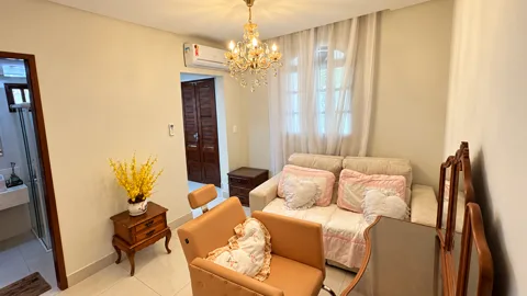 Sala de produção com cadeira de maquiagem, sofá, lustre e banheiro ao lado