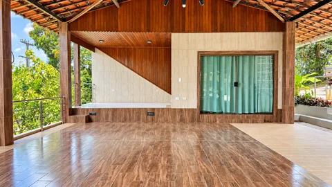 Salão coberto com piso de madeira, palco e vista para o verde