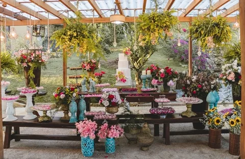 Mesa de doces rústica decorada com flores no jardim