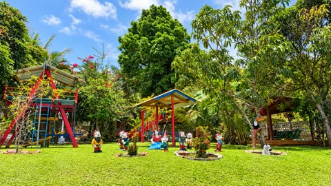 Jardim com anõezinhos decorativos, parquinho e quiosque ao fundo
