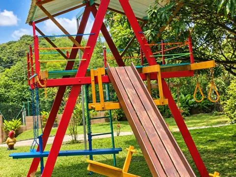 Playground de madeira colorido com escorregador, balanço e argolas
