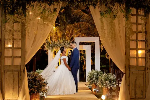 Casal no portal de cortinas iluminado durante cerimônia noturna